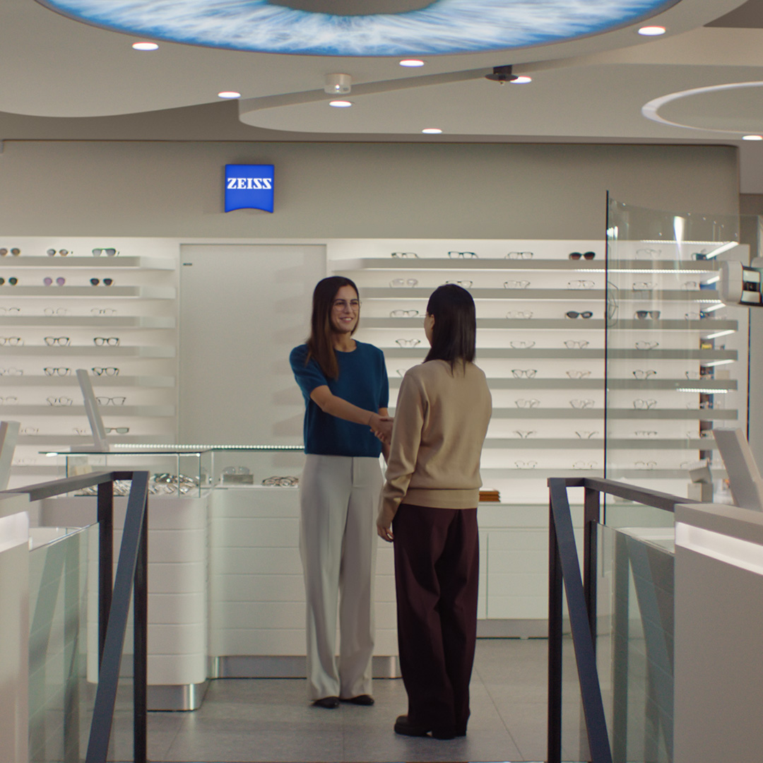 Two women shaking hands in an optician store.