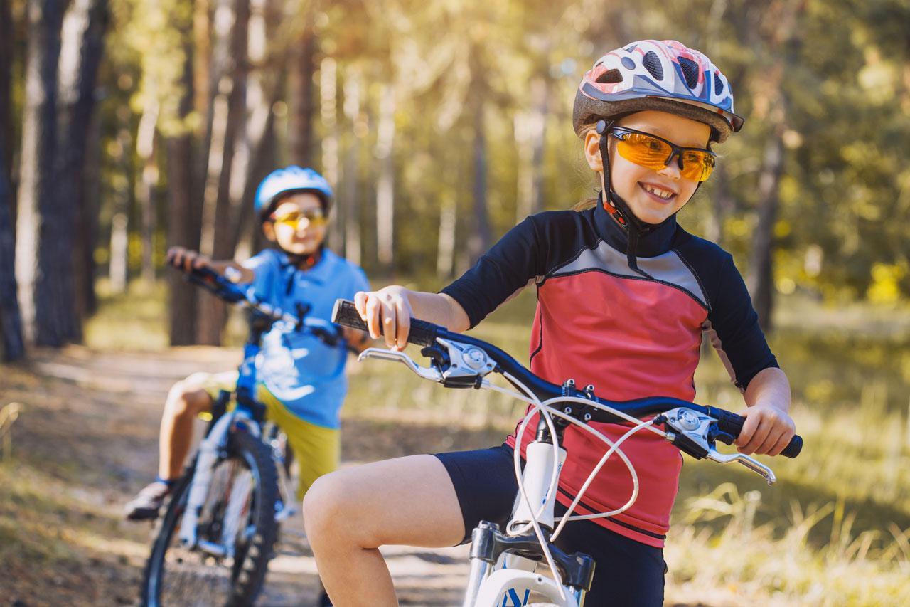 Kids on bicycles in the sunny forest. 