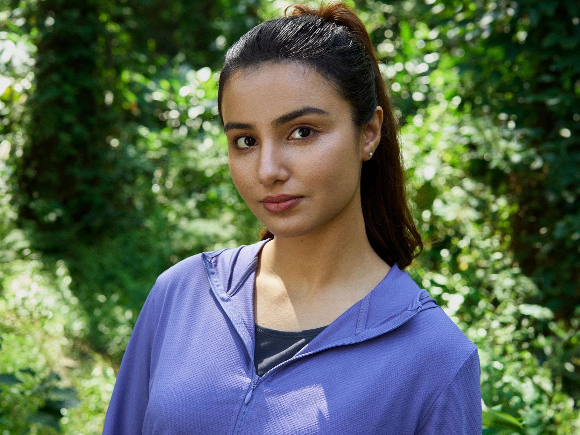 Young woman looks into the horizon. She has dark blond hair and is wearing a gray hoodie.