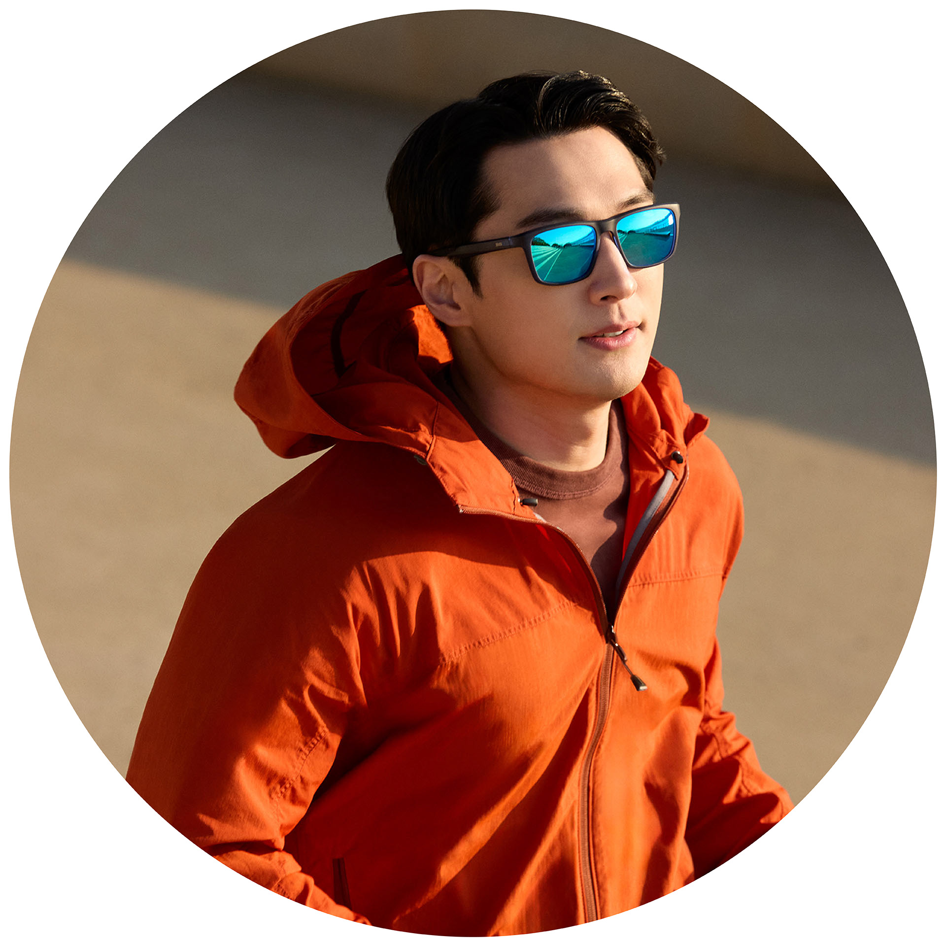 A jogger in an orange jacket wearing ZEISS prescription sunglasses with a blue mirror coating.