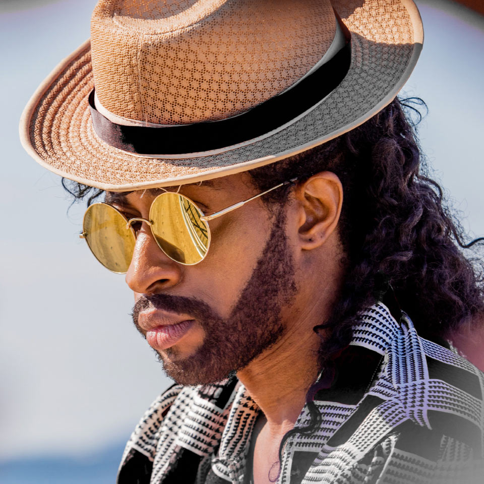 A man on the beach wears golden mirror sunglasses.