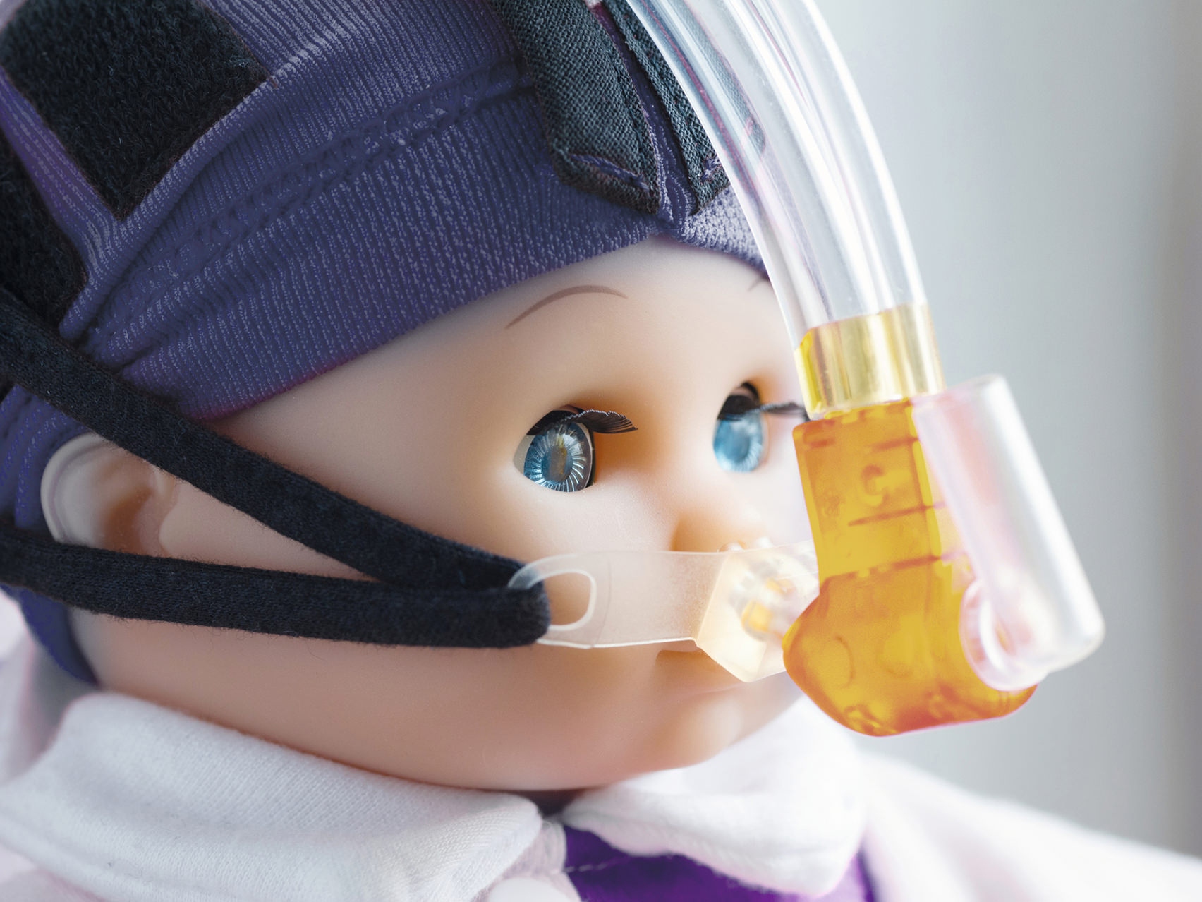 Close-up of a doll face wearing a breathing mask.